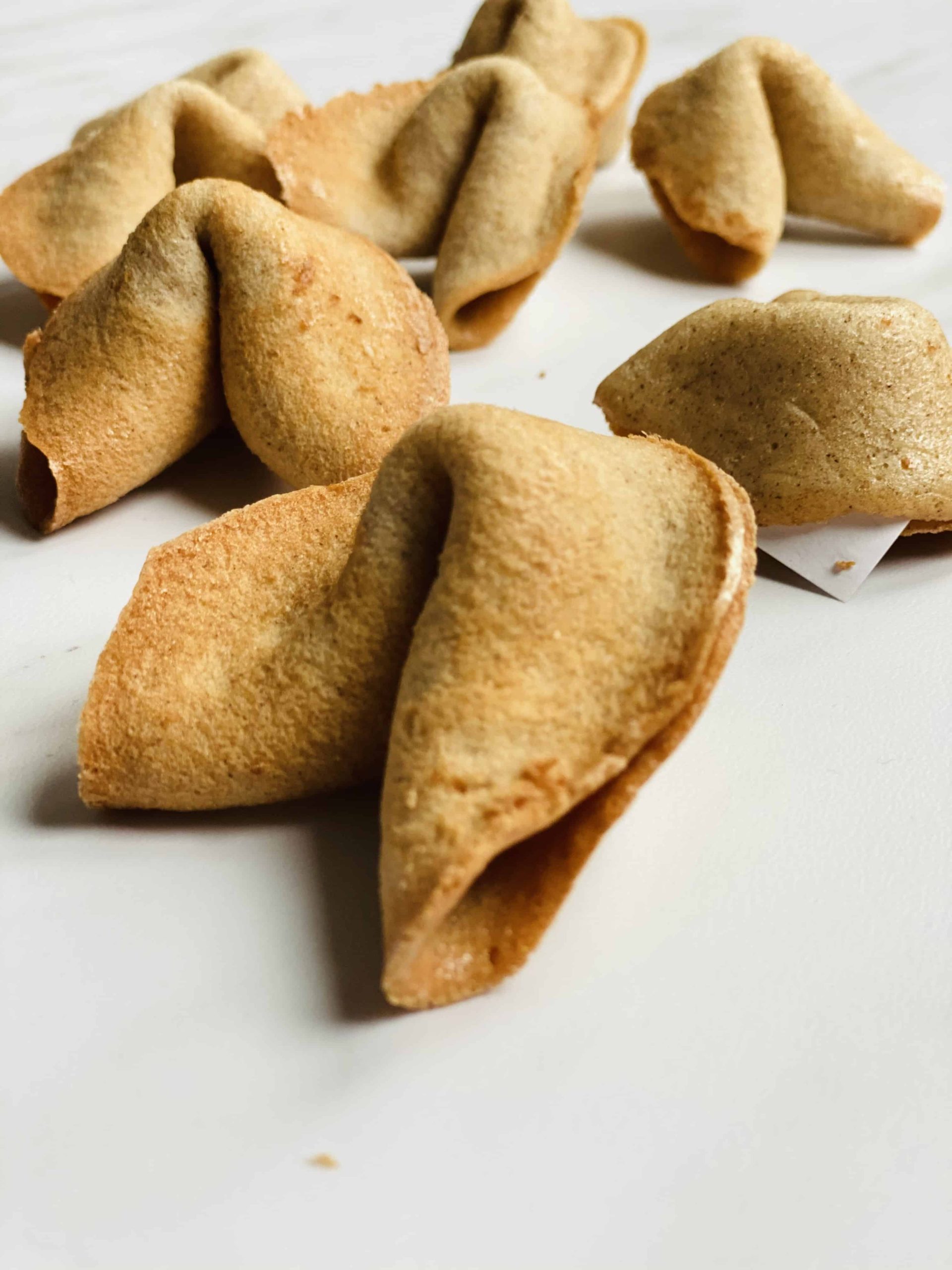 Half a dozen fortune cookies spread out on marble surface.