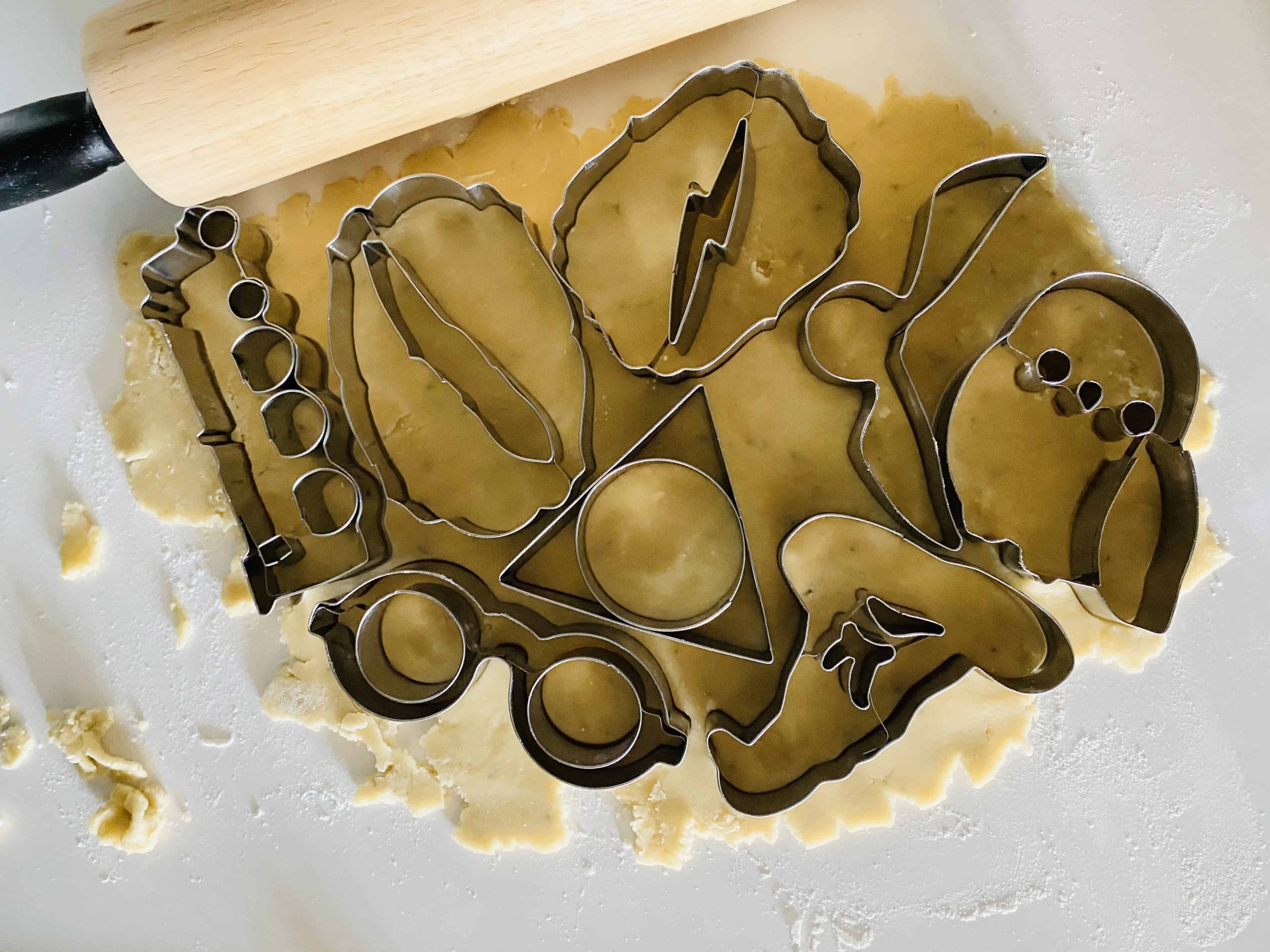 Harry Potter-themed cookie cutters laid out on rolled-out sugar cookie dough.