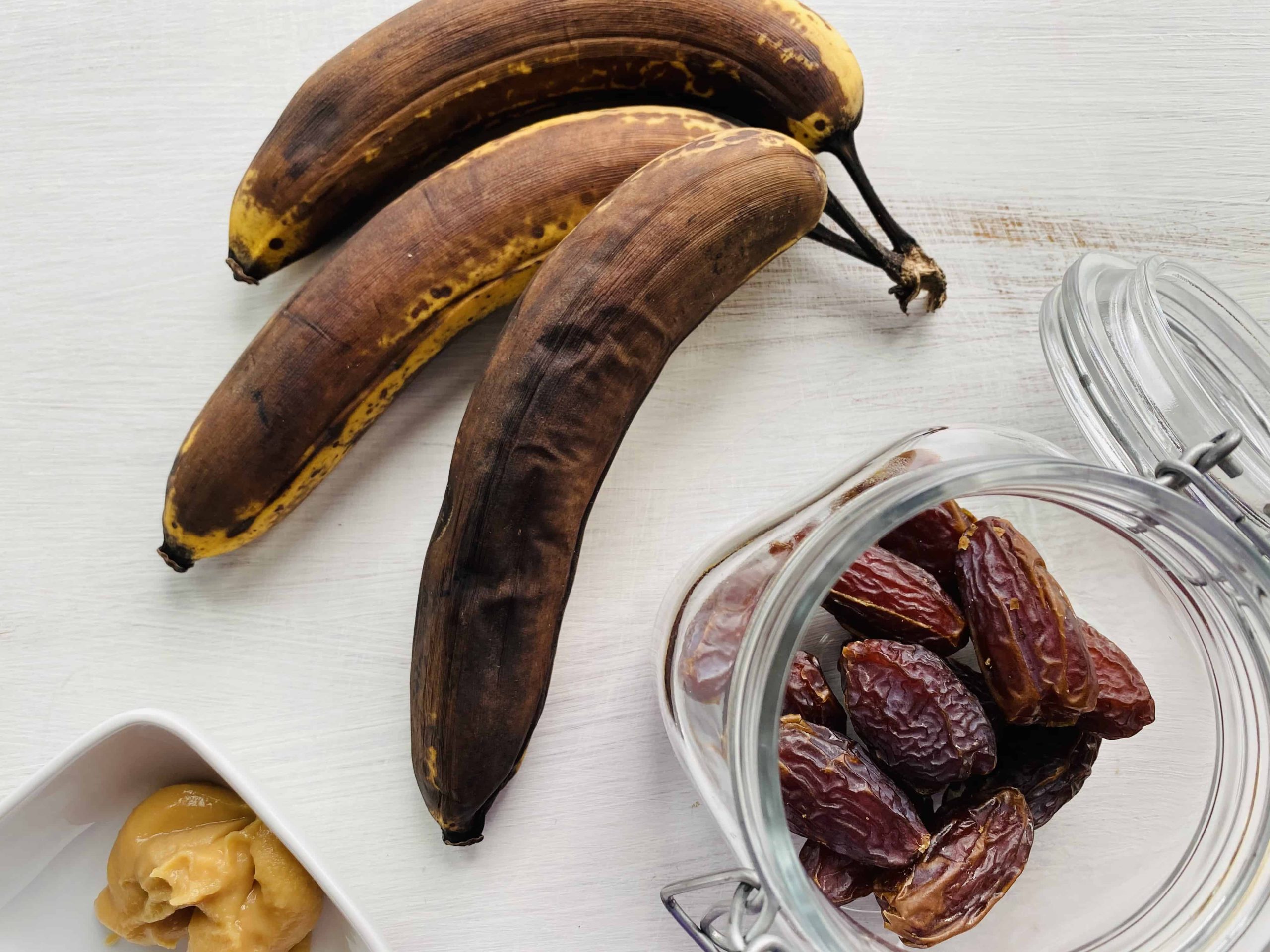 overripe brown bananas, a jar of dates and a small dish of miso paste.