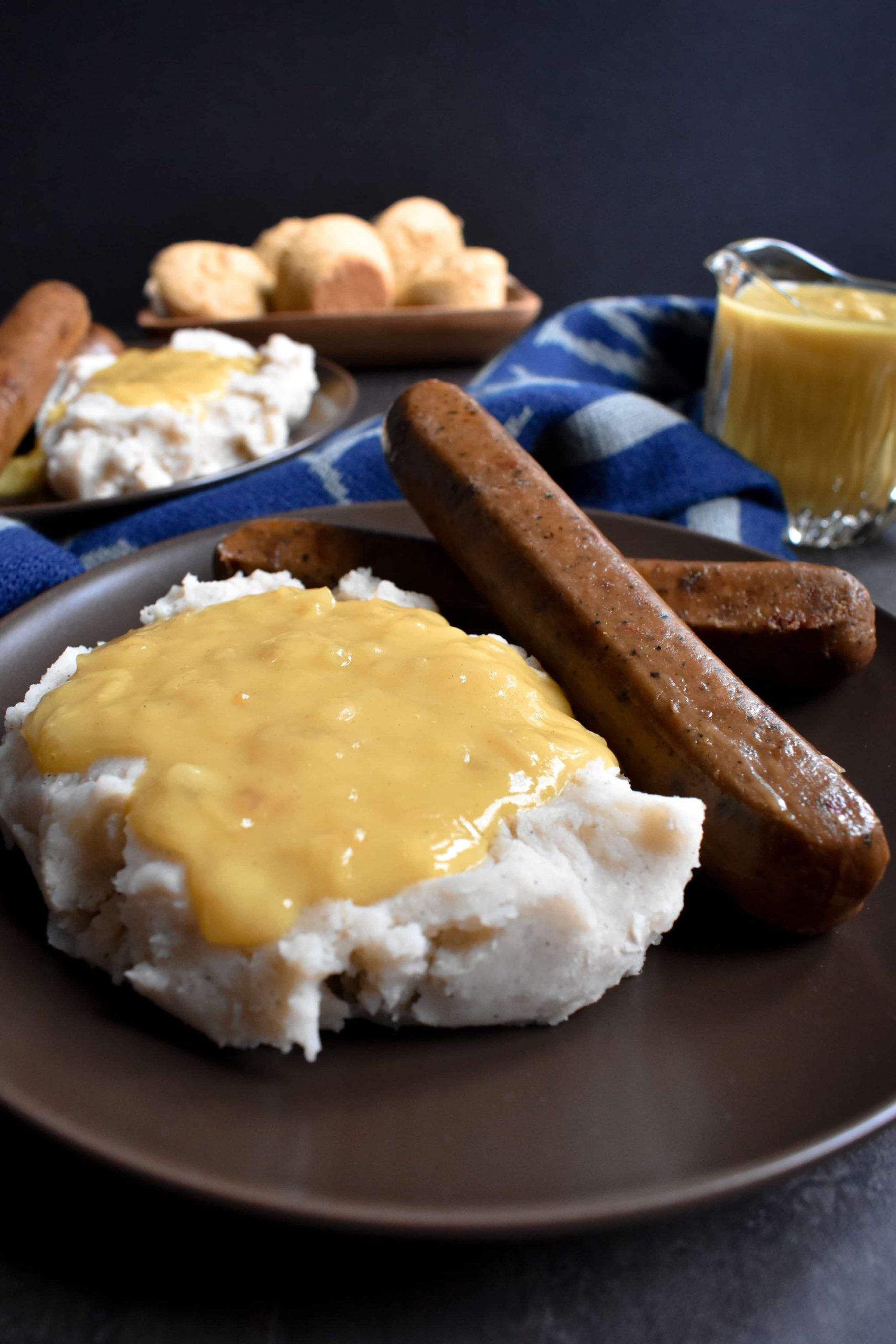 A plate of bangers and mash, topped with yellow gravy.