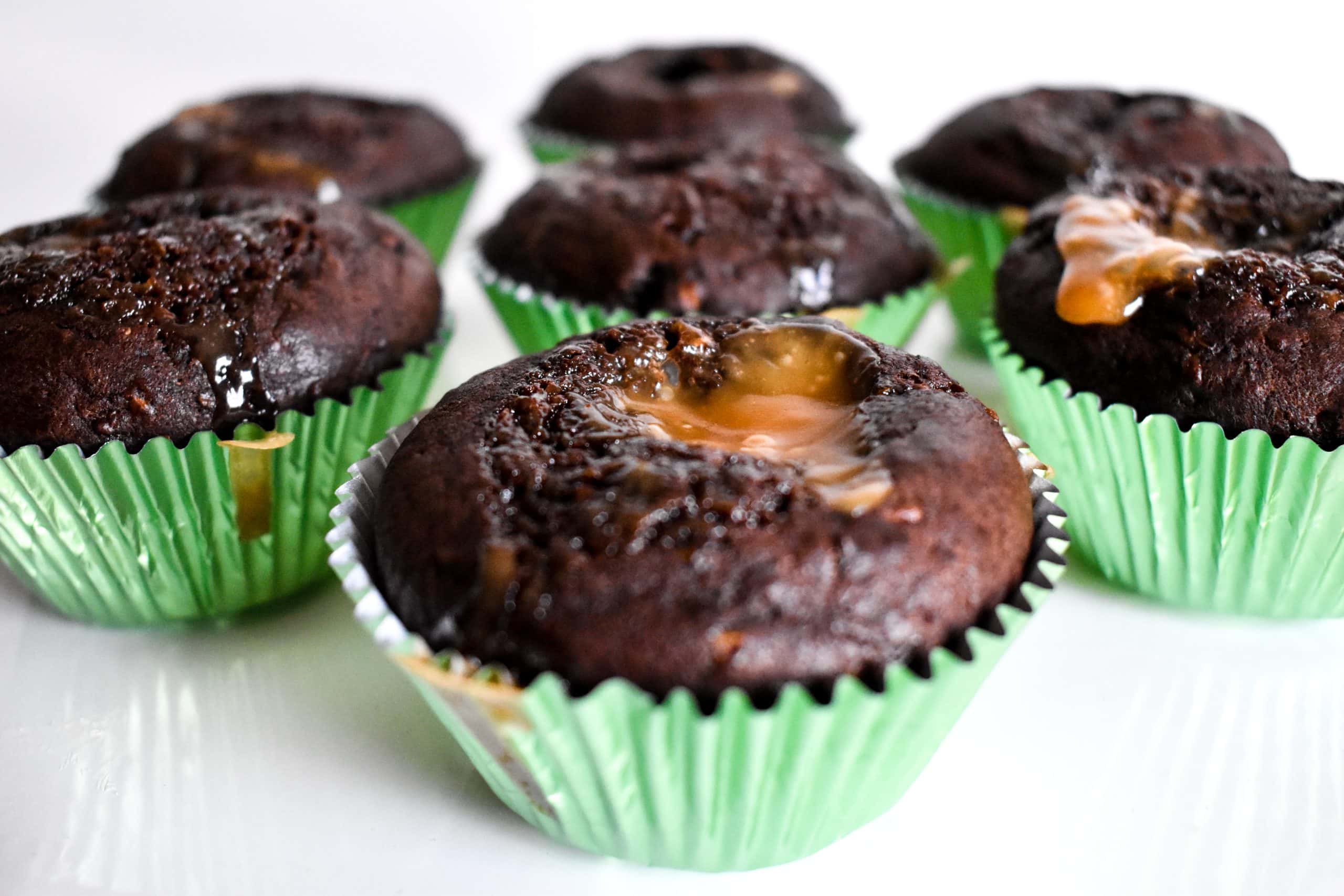 Close-up of seven chocolate zucchini muffins topped with melted caramel.