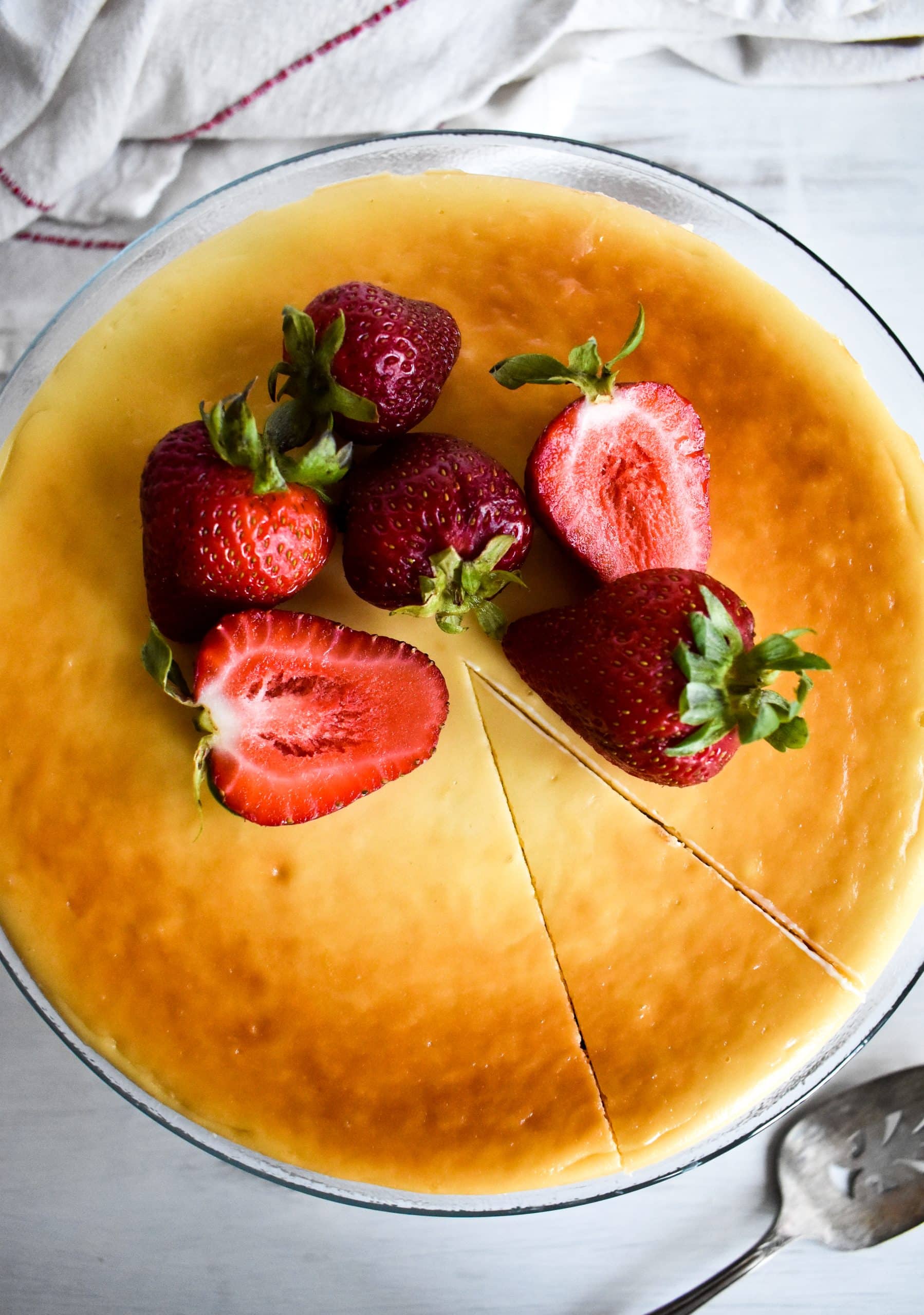 An overhead look at a golden dairy free cheesecake topped with fresh sliced strawberries.