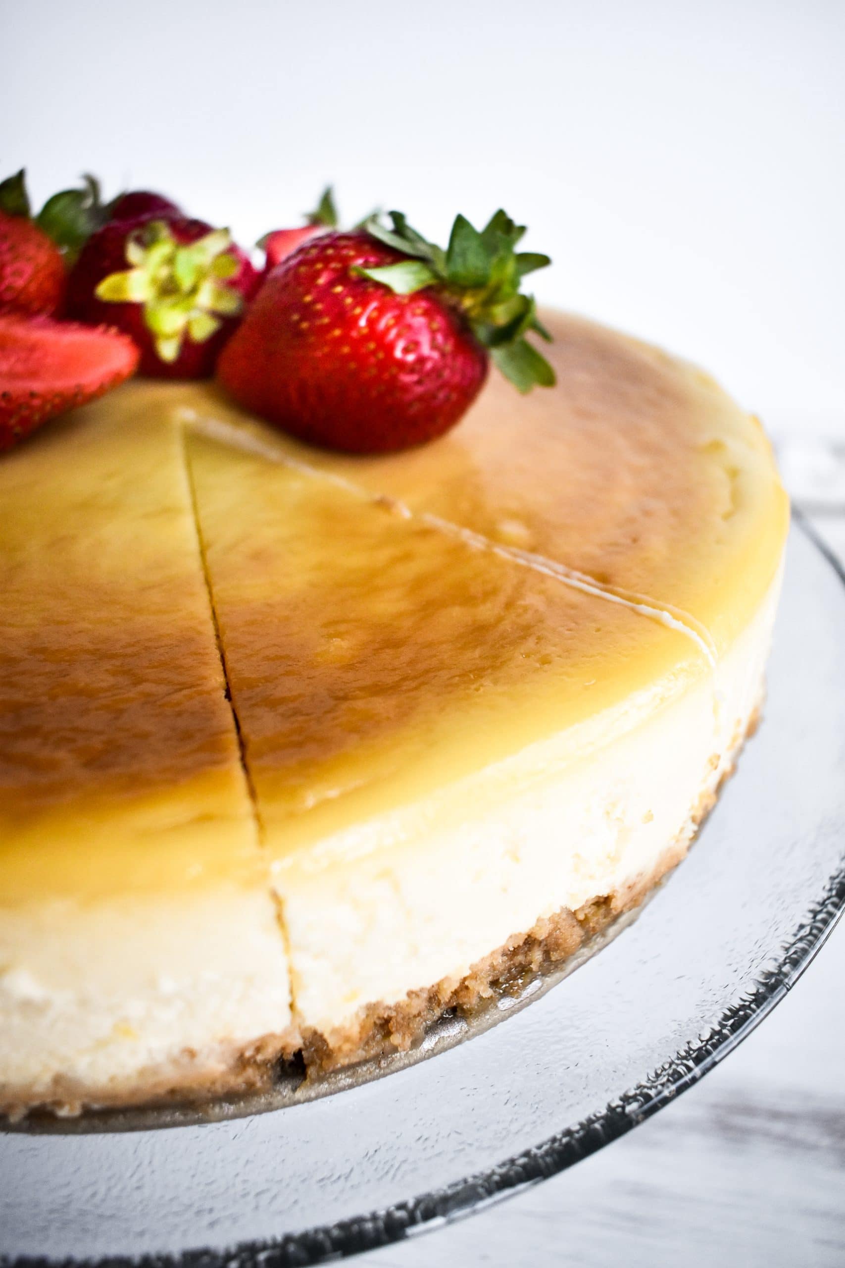 A slice of dairy free cheesecake cut from the whole cake topped with strawberries.