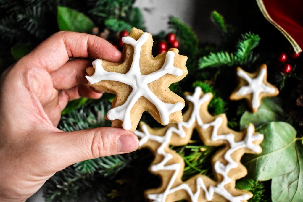 a hand holding a lemon shortbread Christmas cookie