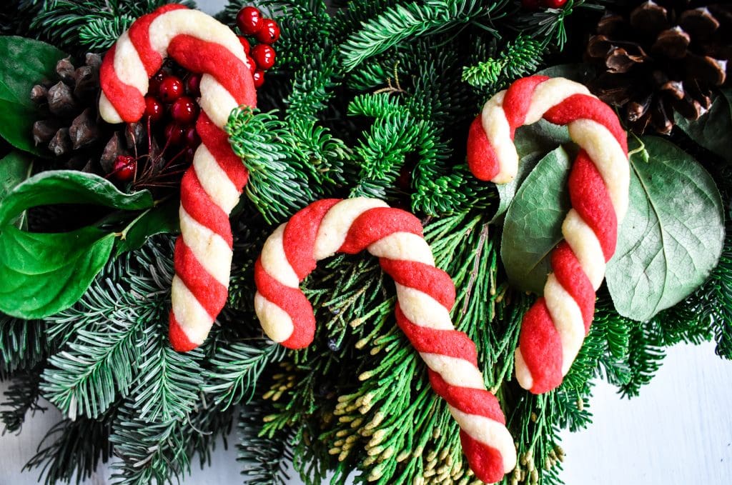 three candy cane cookies laid out on a Winter wreath