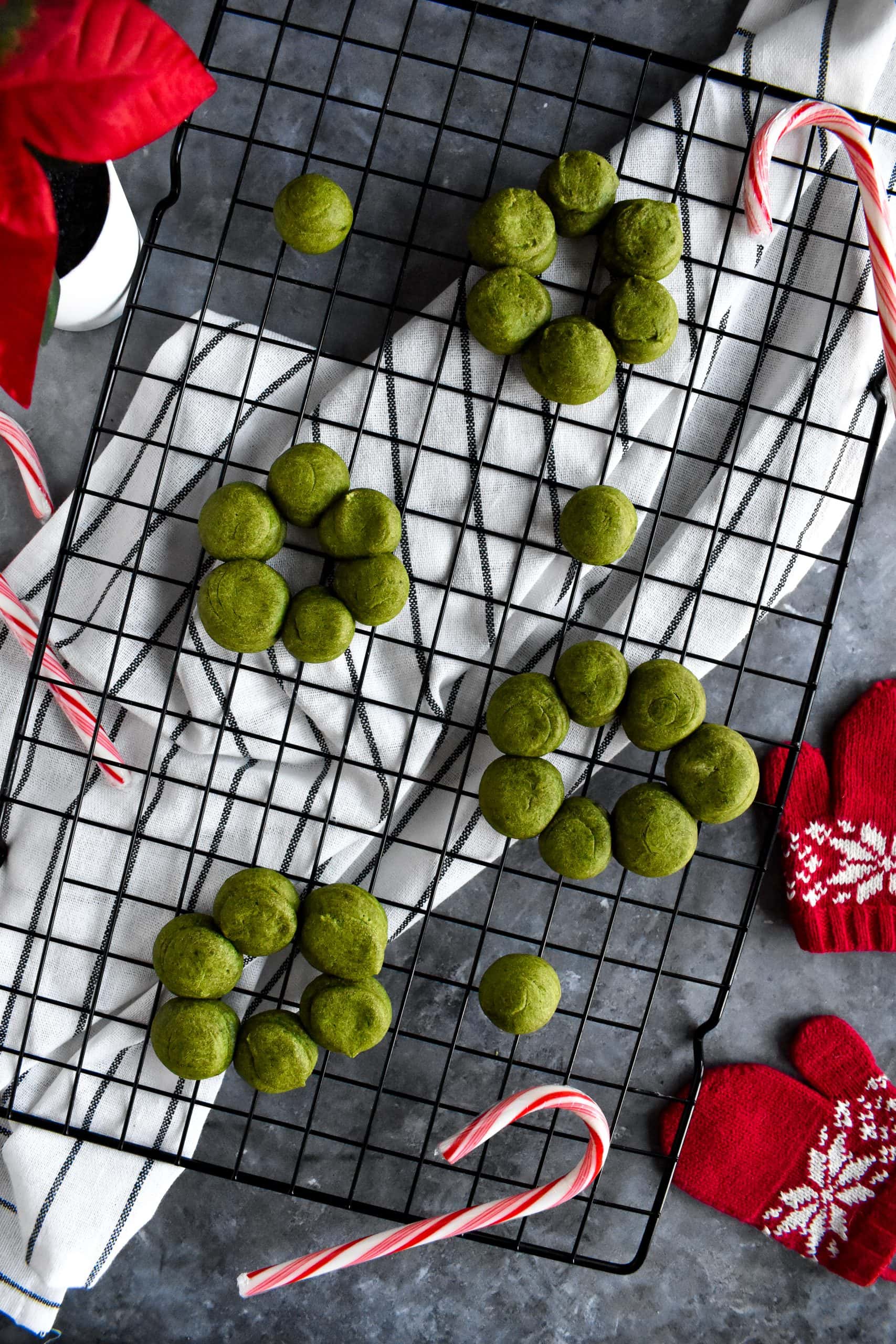 Baked mochi donuts laid out on a black cooling rack next to candy canes.
