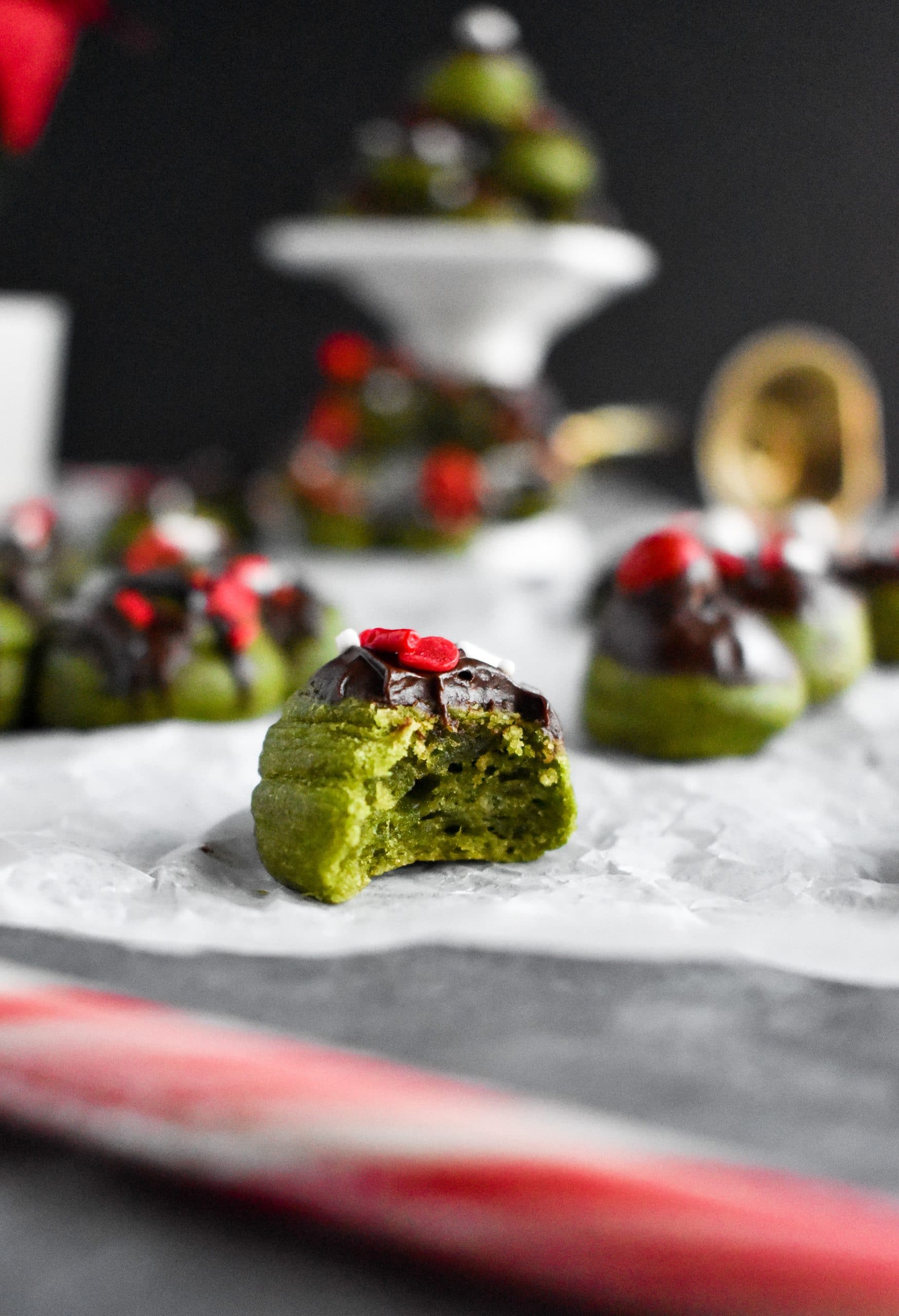A small matcha mochi donut bubble covered in melted chocolate with a bite taken out of it.