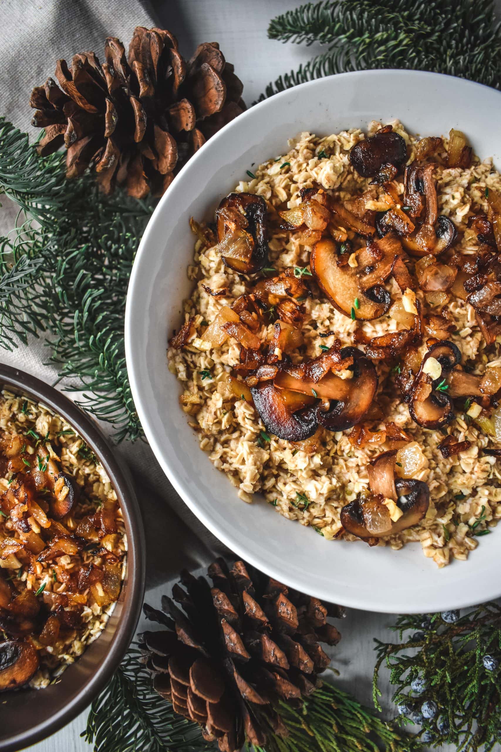 Two bowls of savory oatmeal topped with caramelized mushrooms, onions, and chopped thyme. 