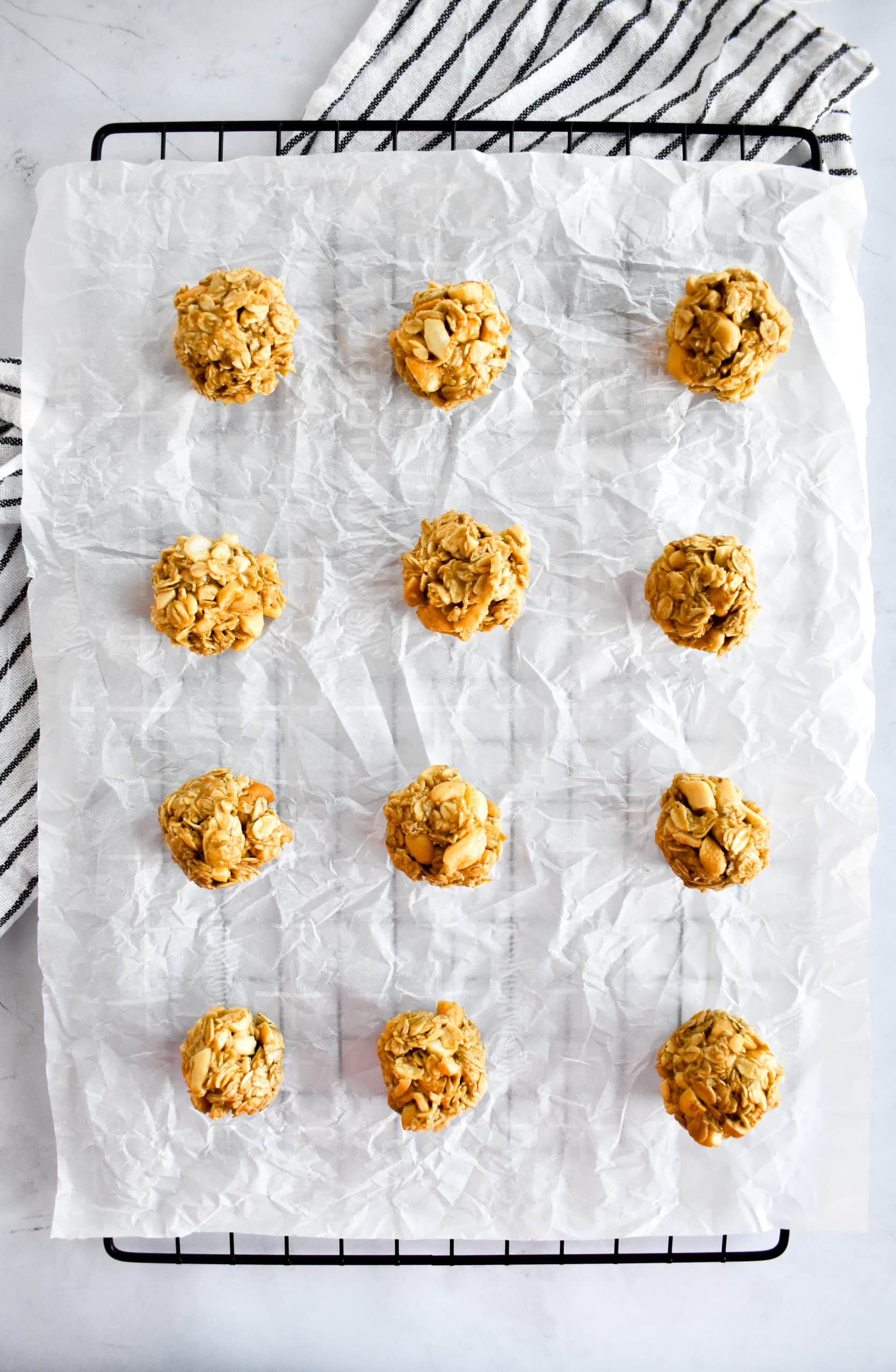 A cooling rack topped with parchment paper and a dozen peanut and cashew energy bites.