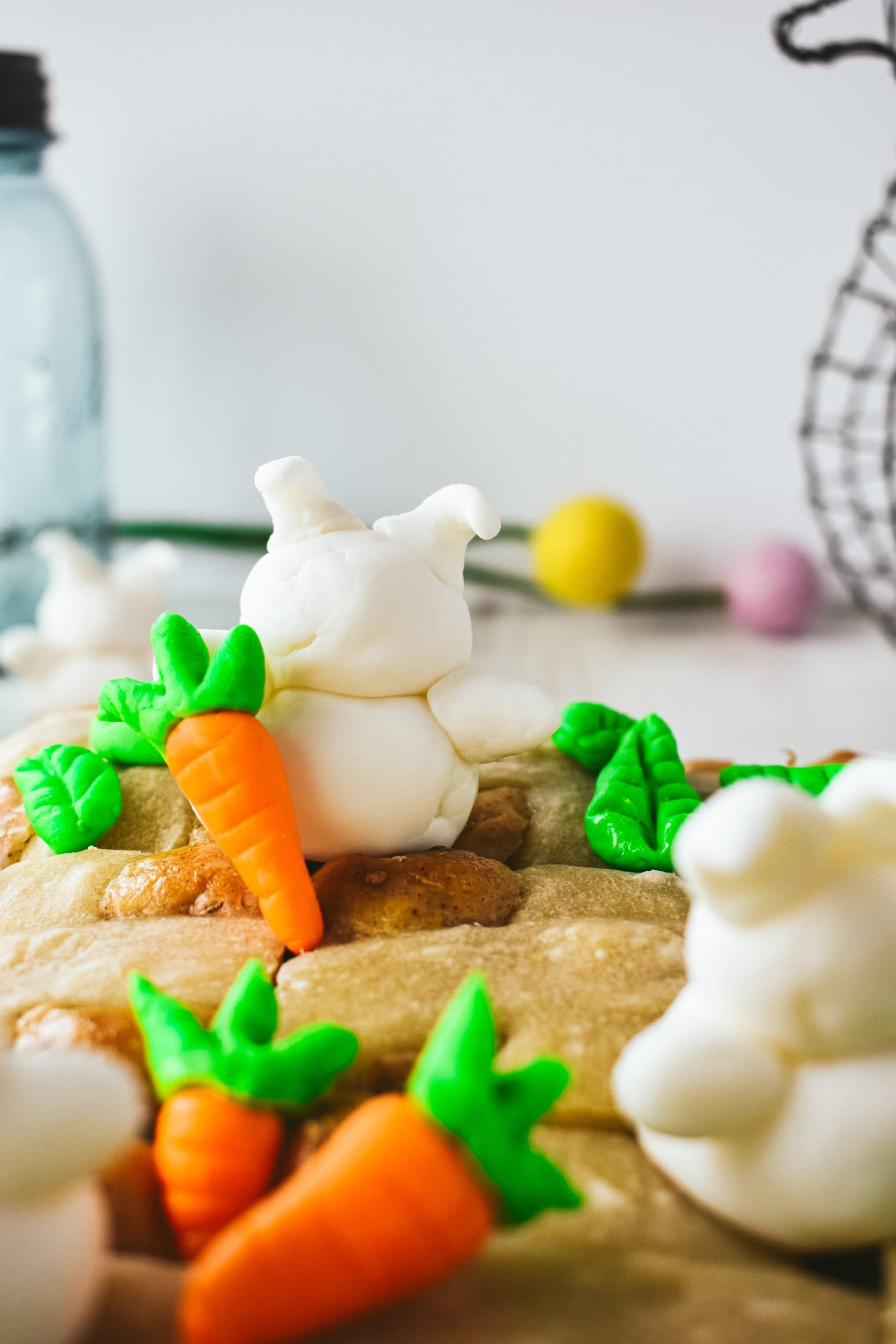 Baked bread buns with orange and green fondant carrots and white fondant bunnies on top.