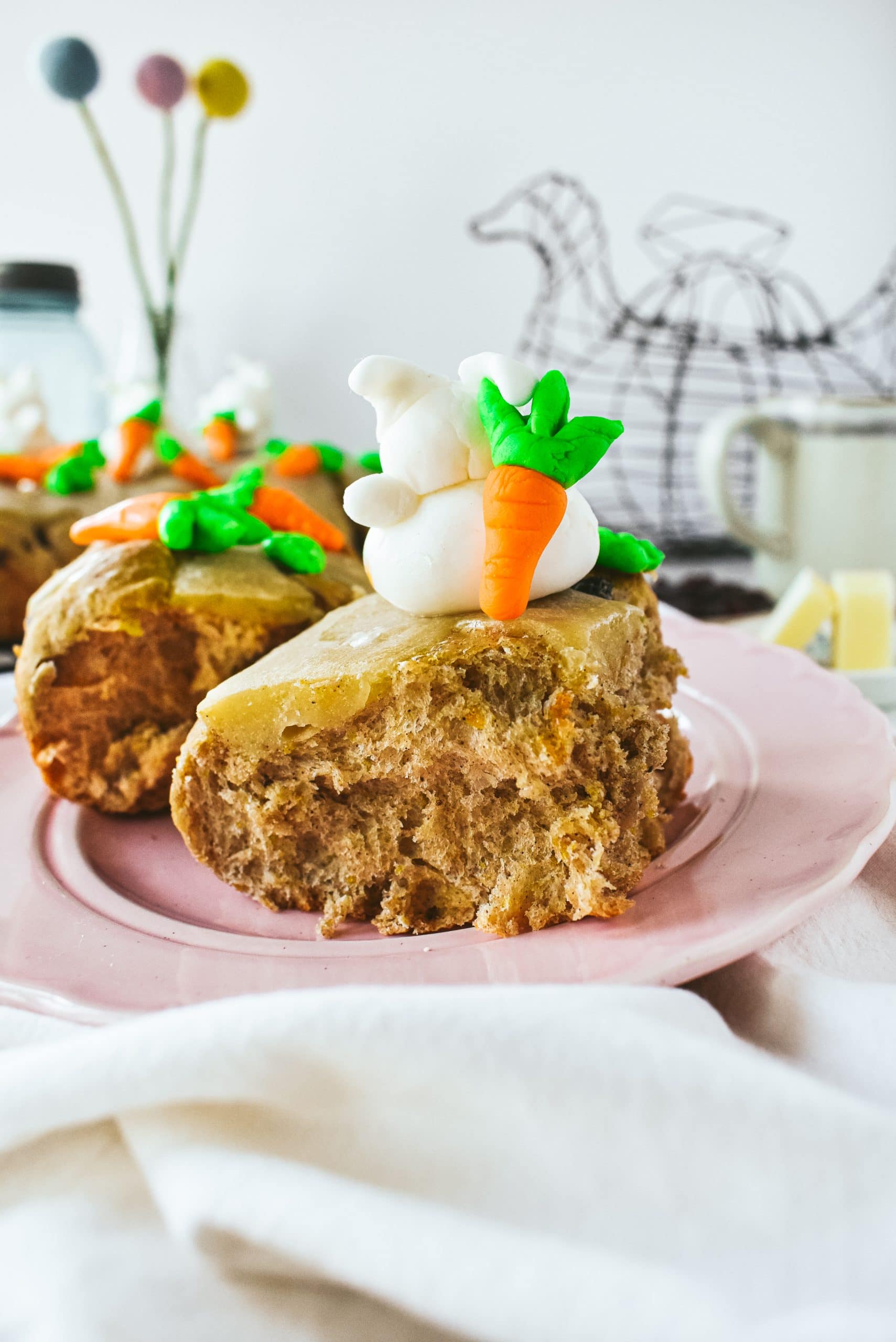 Two hot cross buns on a pink plate.