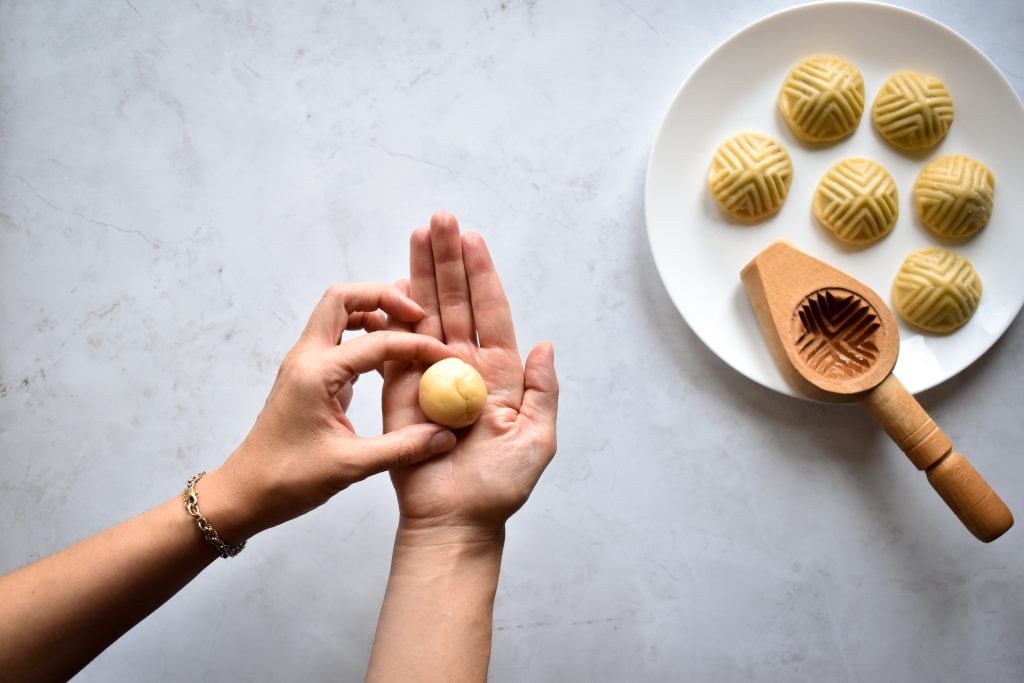 two hands shaping the dough to make maamoul