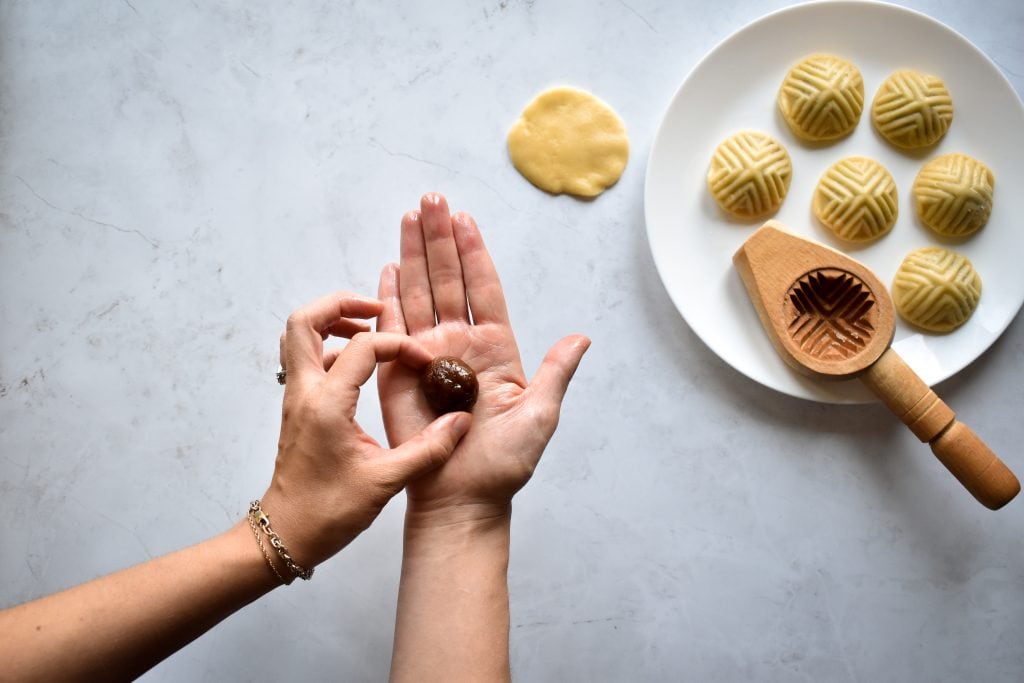 two hands forming the date filling to make middle eastern date cookies