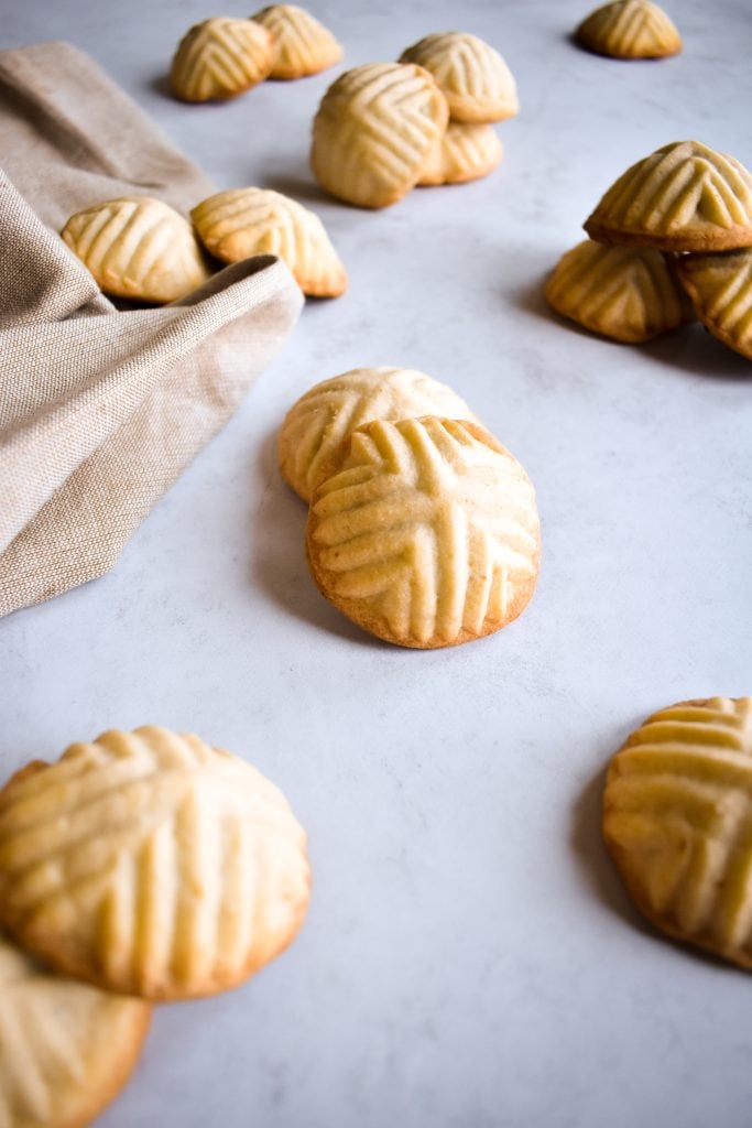 two dozen Maamoul (Mamool) - Date Cookies spread out on a grey surface