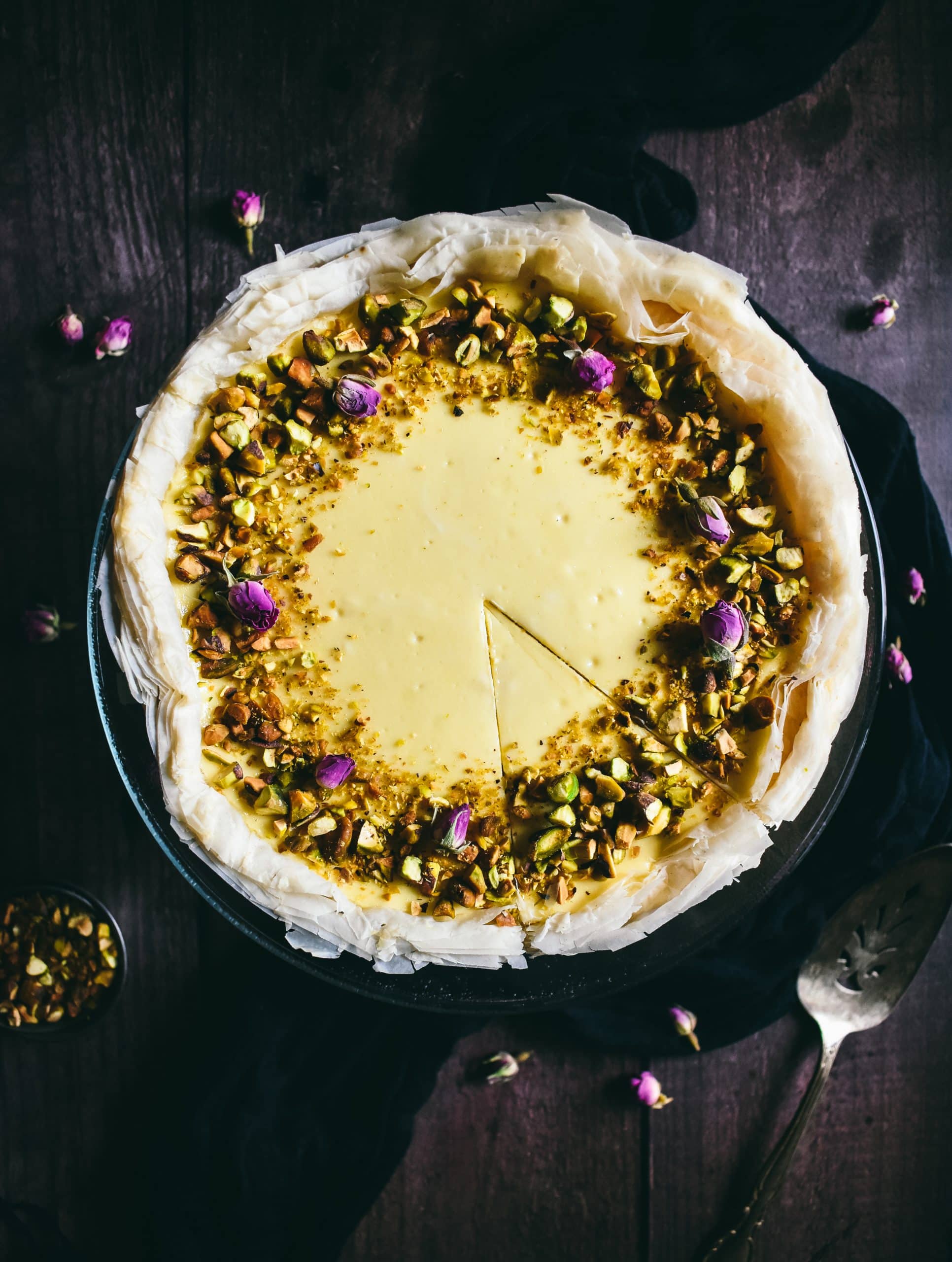 Overhead view of a baklava cheesecake
with a slice cut into it.