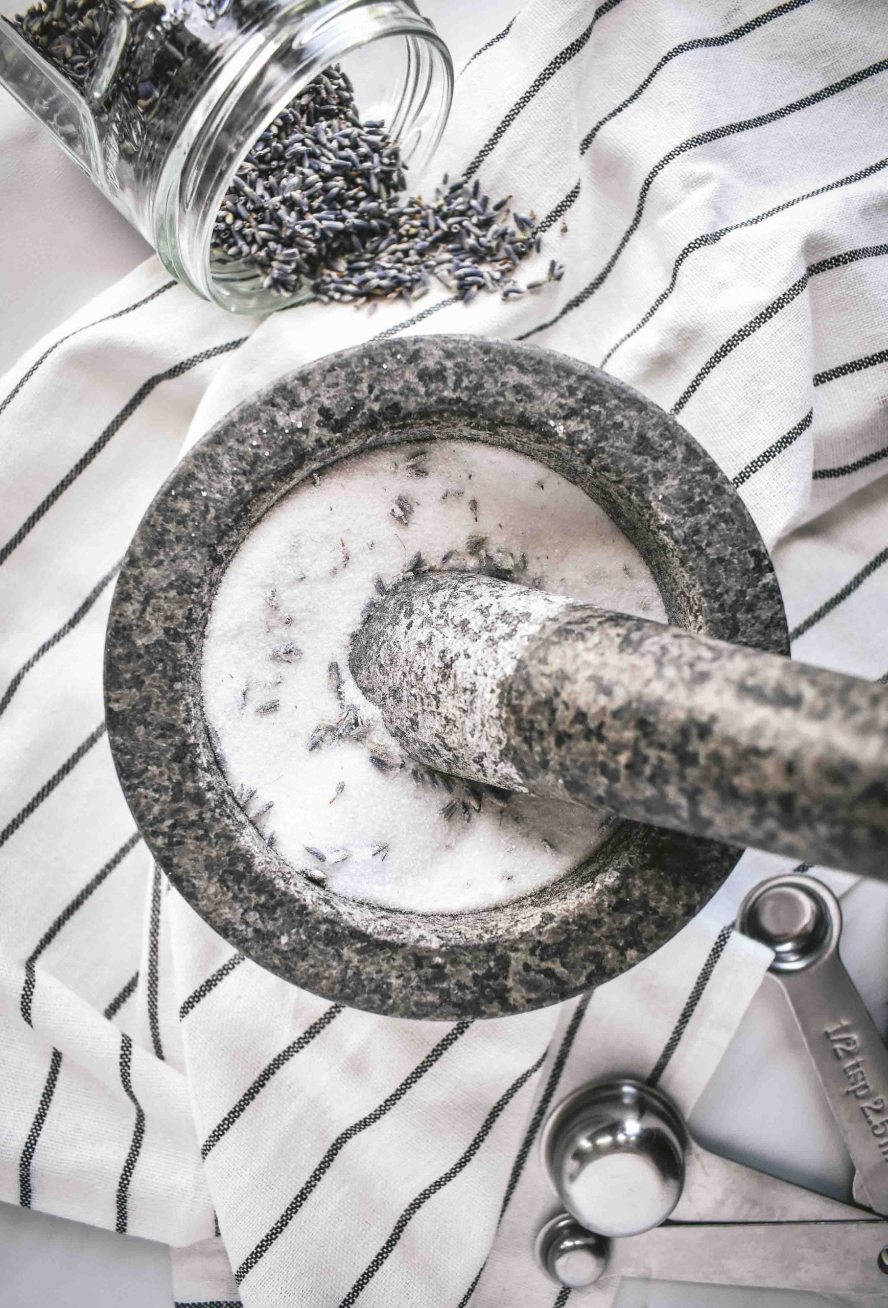 A mortar and pestle filled with white sugar and lavender buds.