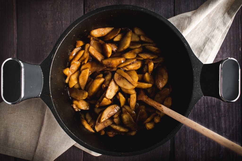 a black pot filled with cooked apple pie filling