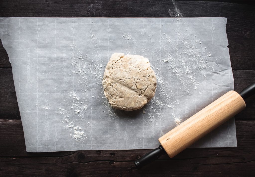 a disc of raw pie dough on a large piece of parchment paper