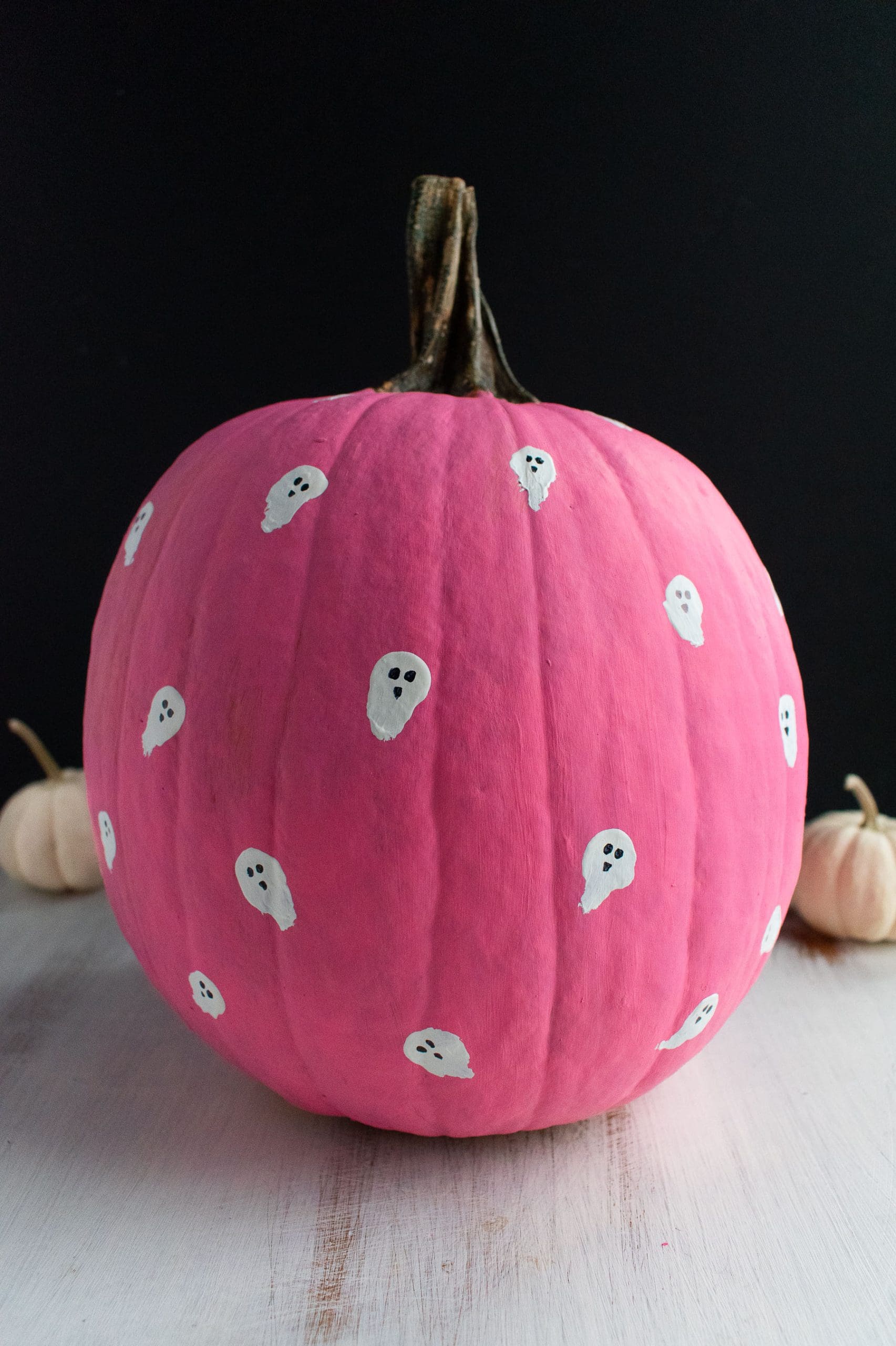 A pink painted pumpkin with little white ghosts. 
