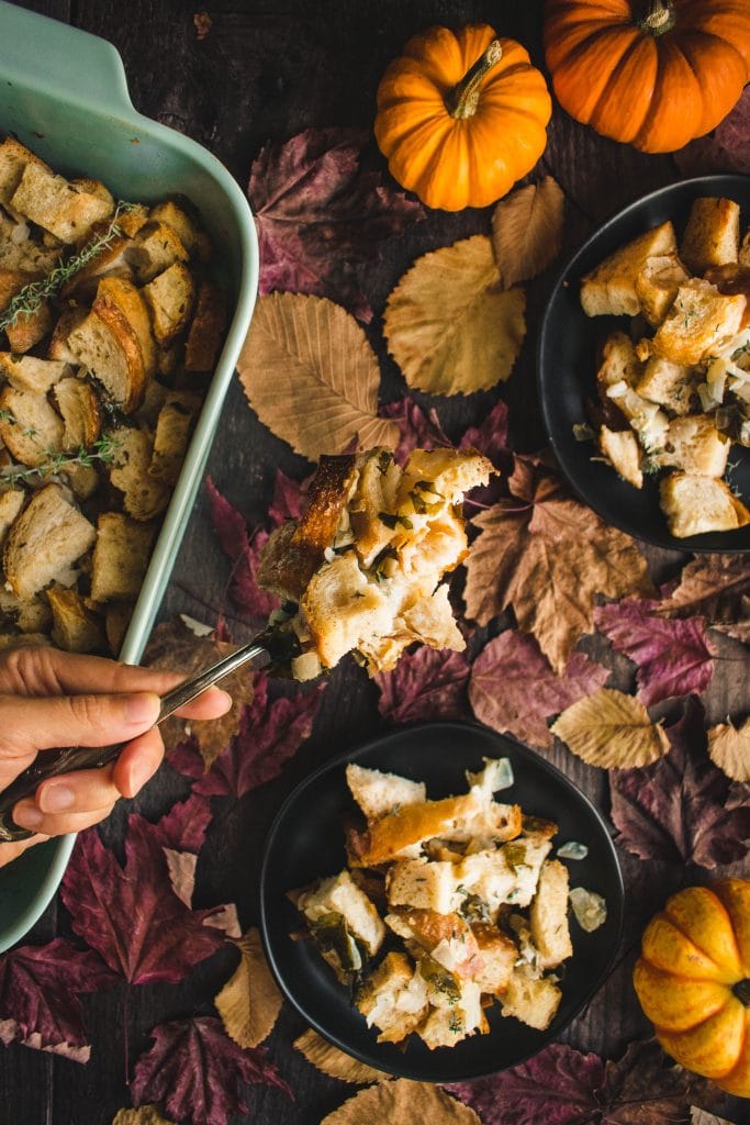 hand serving Sourdough Stuffing from a blue dish