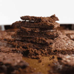 Half a dozen thin brownie chips stacked on top of each other on a metal sheet pan.