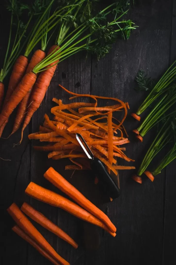 Carrots cut into long pieces on a wooden table.