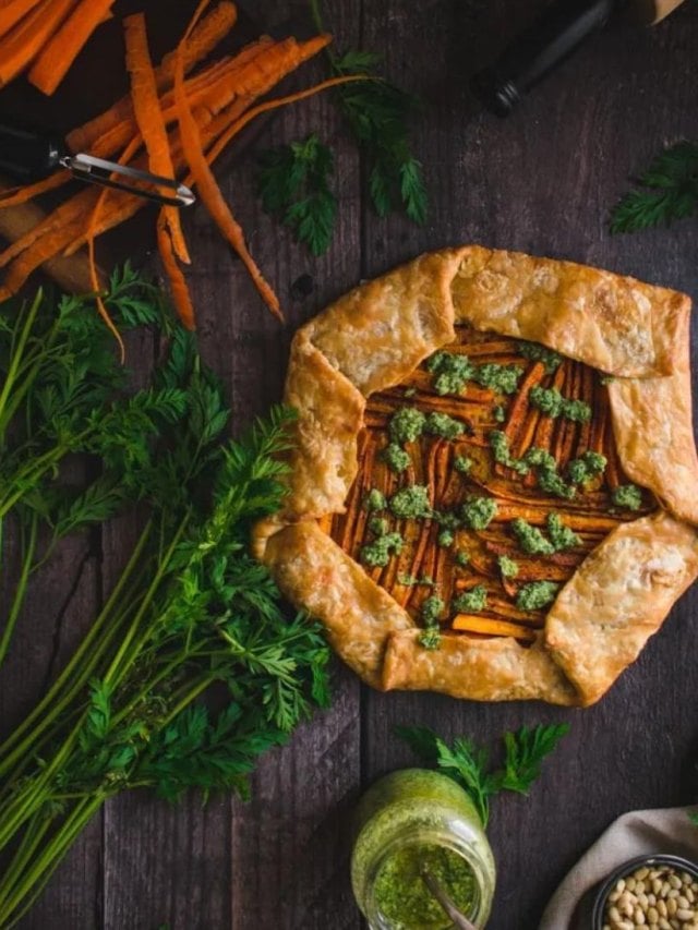 Overhead shot of carrot galette with carrot tops and carrot peels on the side.