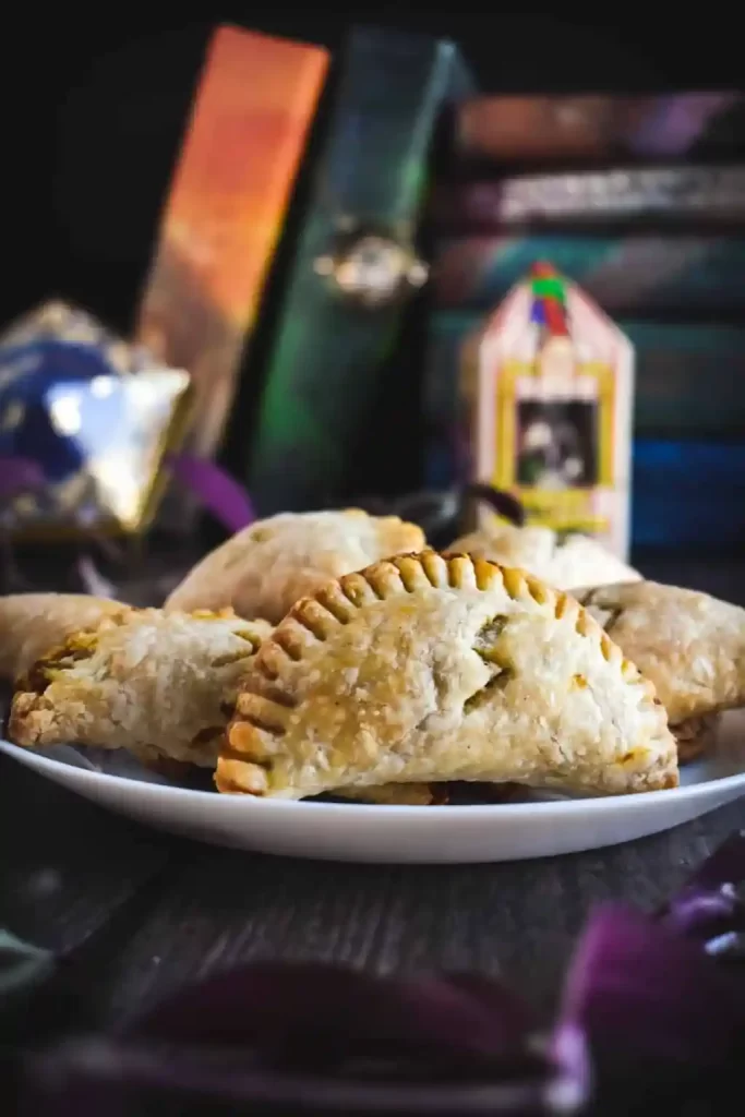 A plate of half-circle pumpkin hand pies next to books.