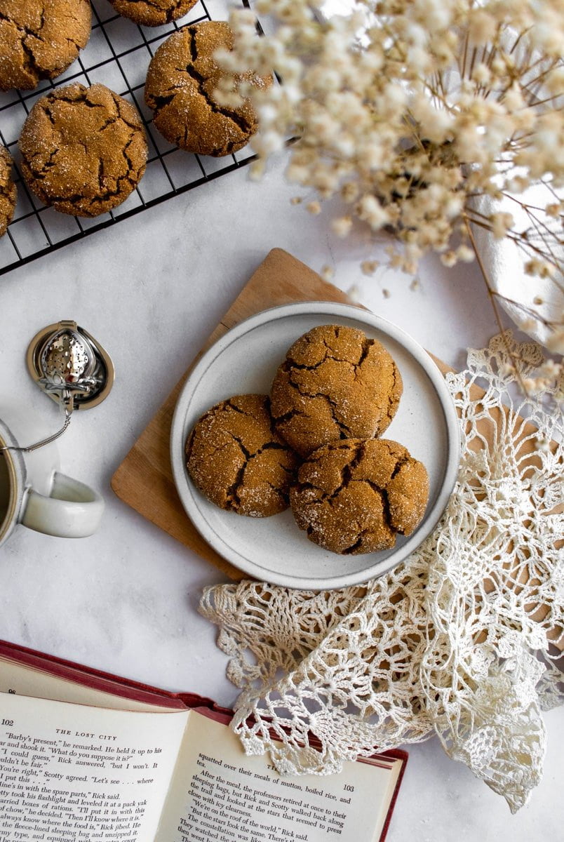 Chewy cookies on a plate next to more cookies on a cooling rack.