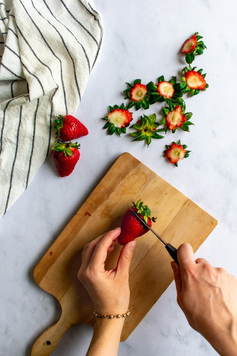 Strawberries being chopped on a board.