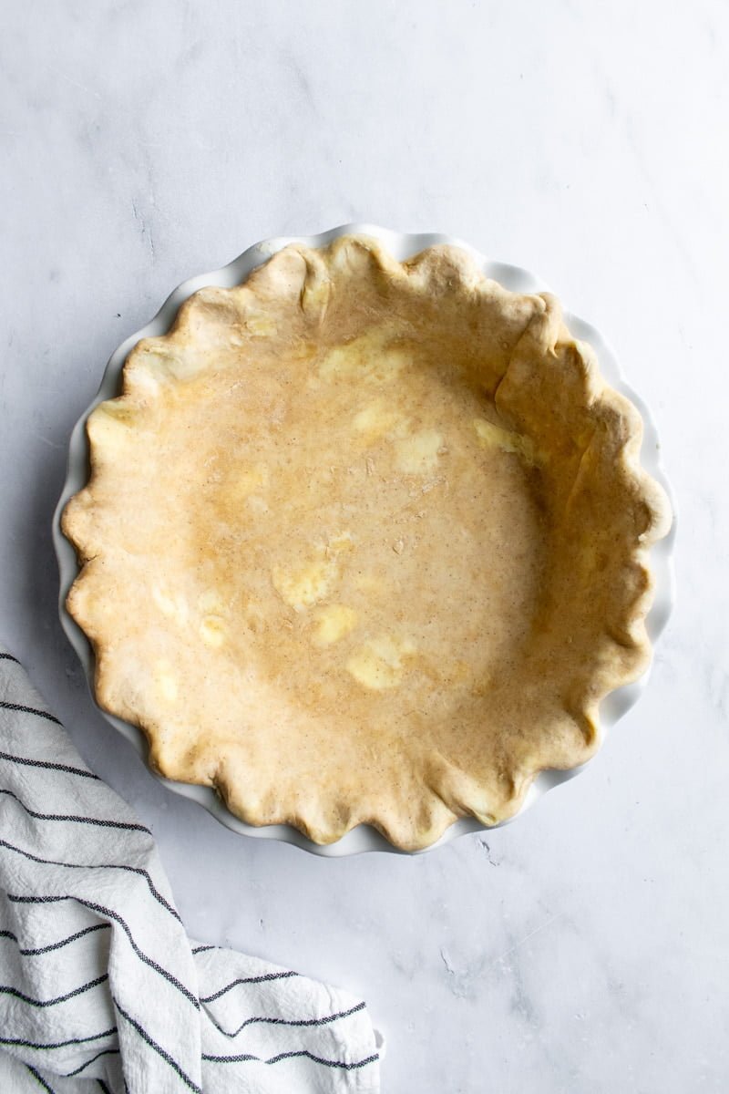 Unbaked pie dough in a pie dish with crimped edges.