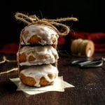 A stack of three glazed Pfeffernusse cookies.