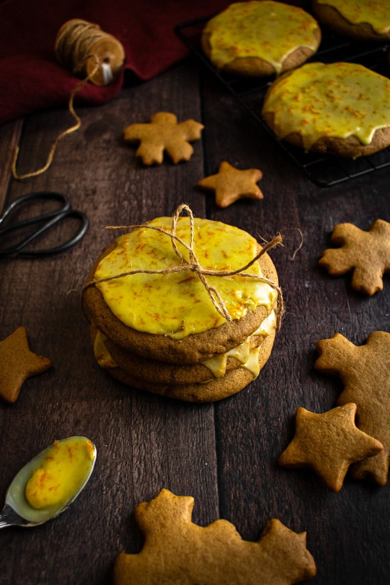 A stack of three Lebkuchen next to gingerbread cut into snowflakes and stars.