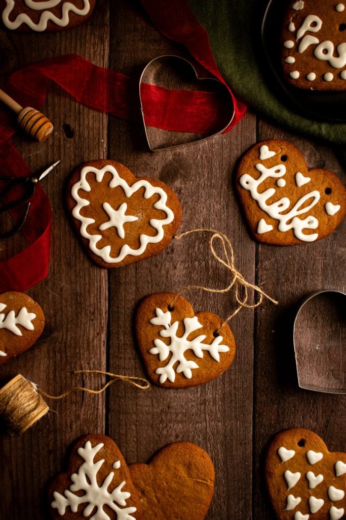 Gingerbread heart cookies topped with white royal icing decorations on a wooden table.