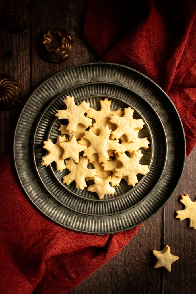 A metal plate filled with golden snowflake-shaped cookies.