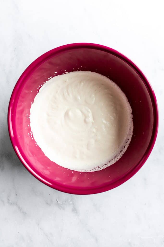 Heavy cream whipped to soft peaks in a pink bowl.