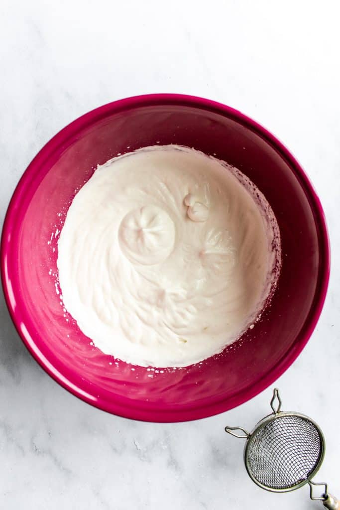 Whipped cream whipped to stiff peaks in a mixing bowl.