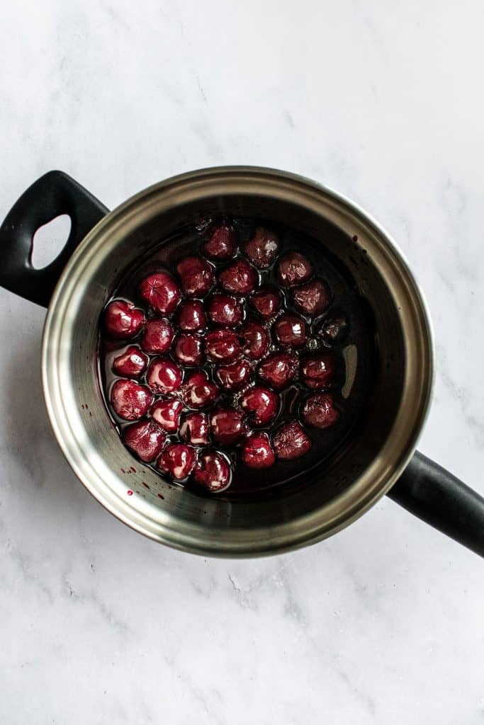 Canned dark cherries in a saucepan.