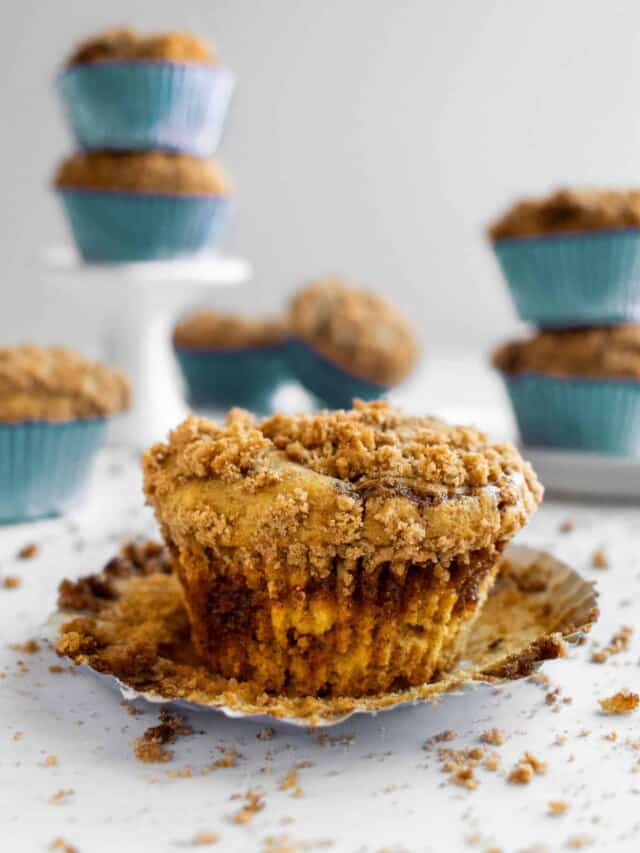 A muffin in a blue muffin liner topped with crumbly streusel. 