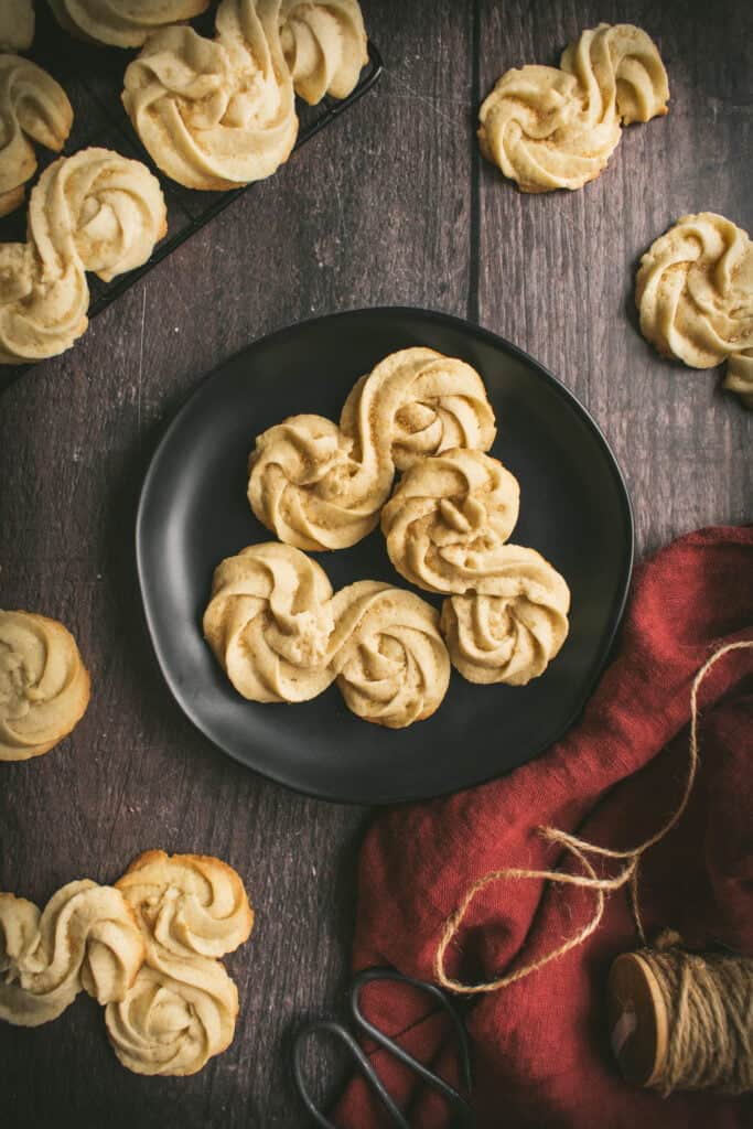 Swirled golden biscuits on a black plate and wooden table.