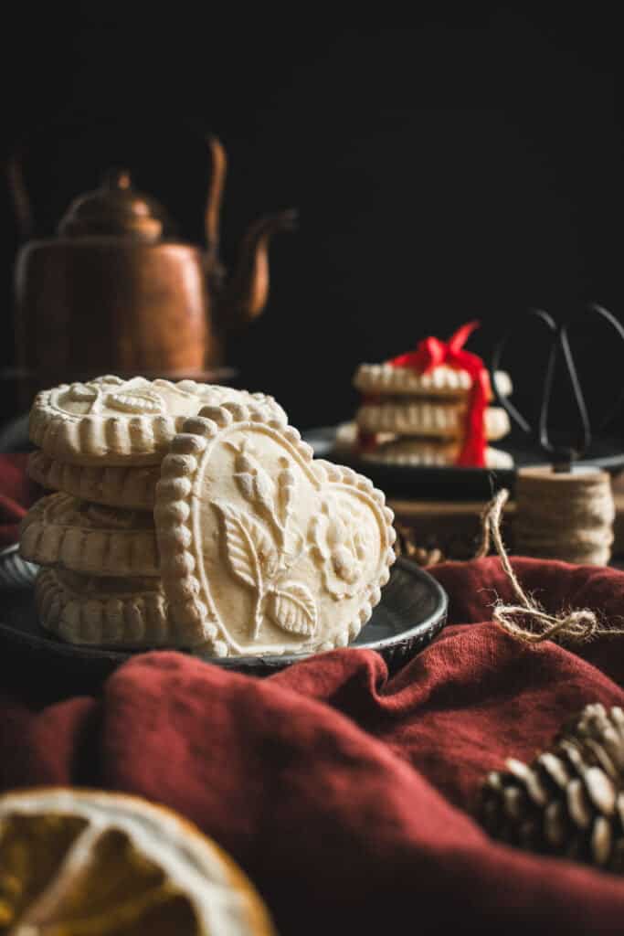 White heart-shaped cookies stacked on plates and a red linen.