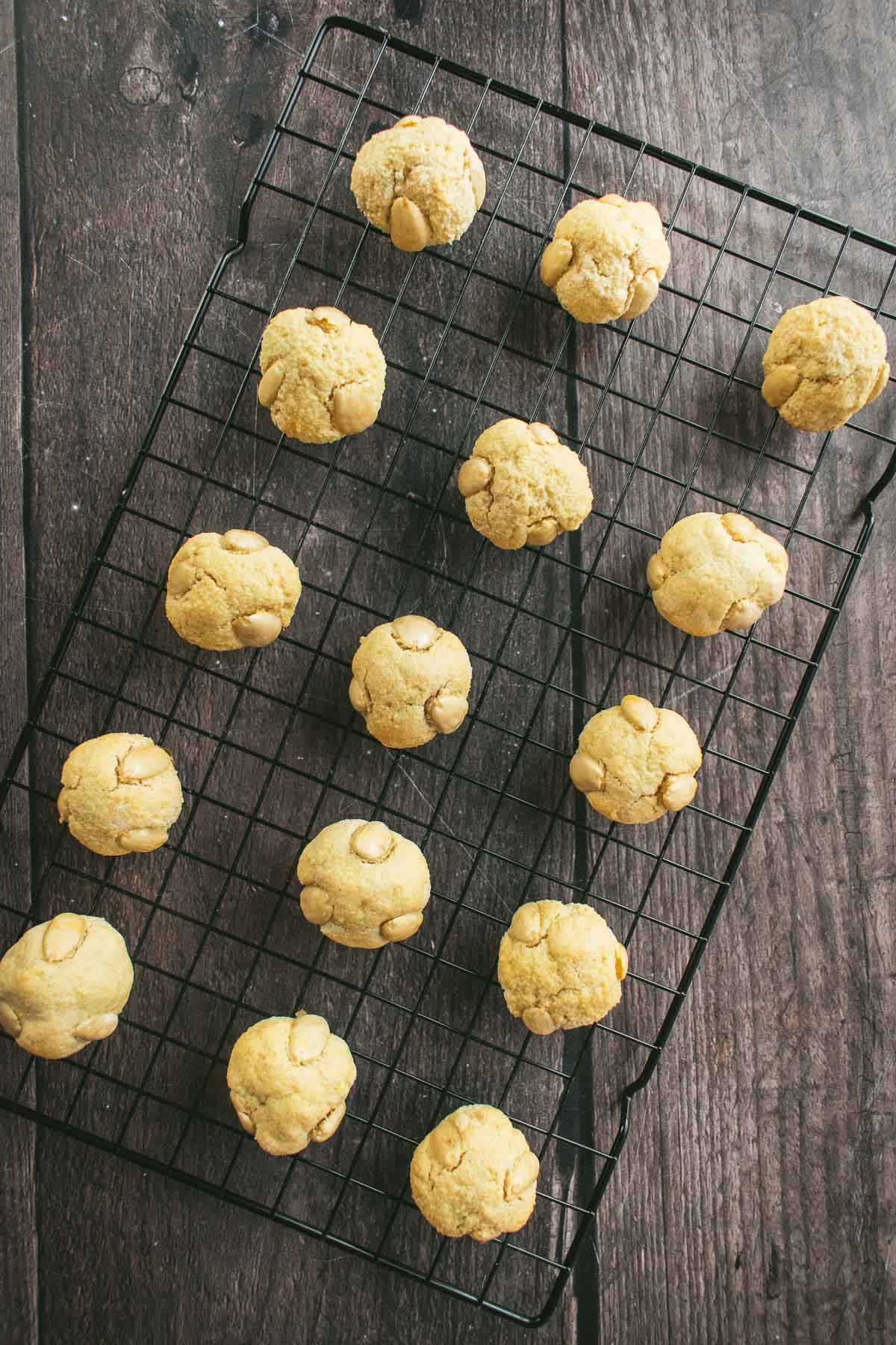 Fifteen baked marzipan cookies lined up on a wire cooling rack.