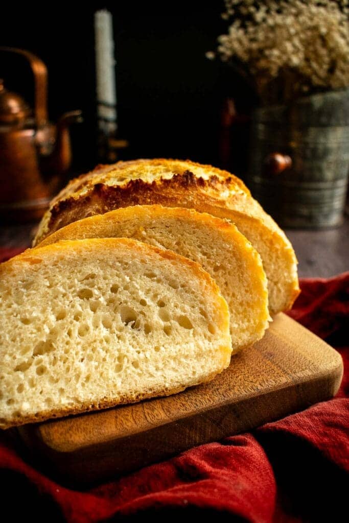 Two slices of white bread leaning against the rest of the loaf.