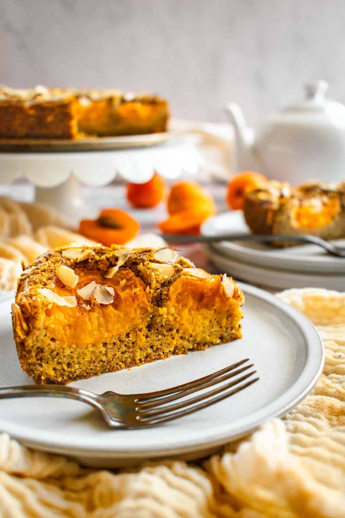 A slice of apricot and almond cake on a grey plate.