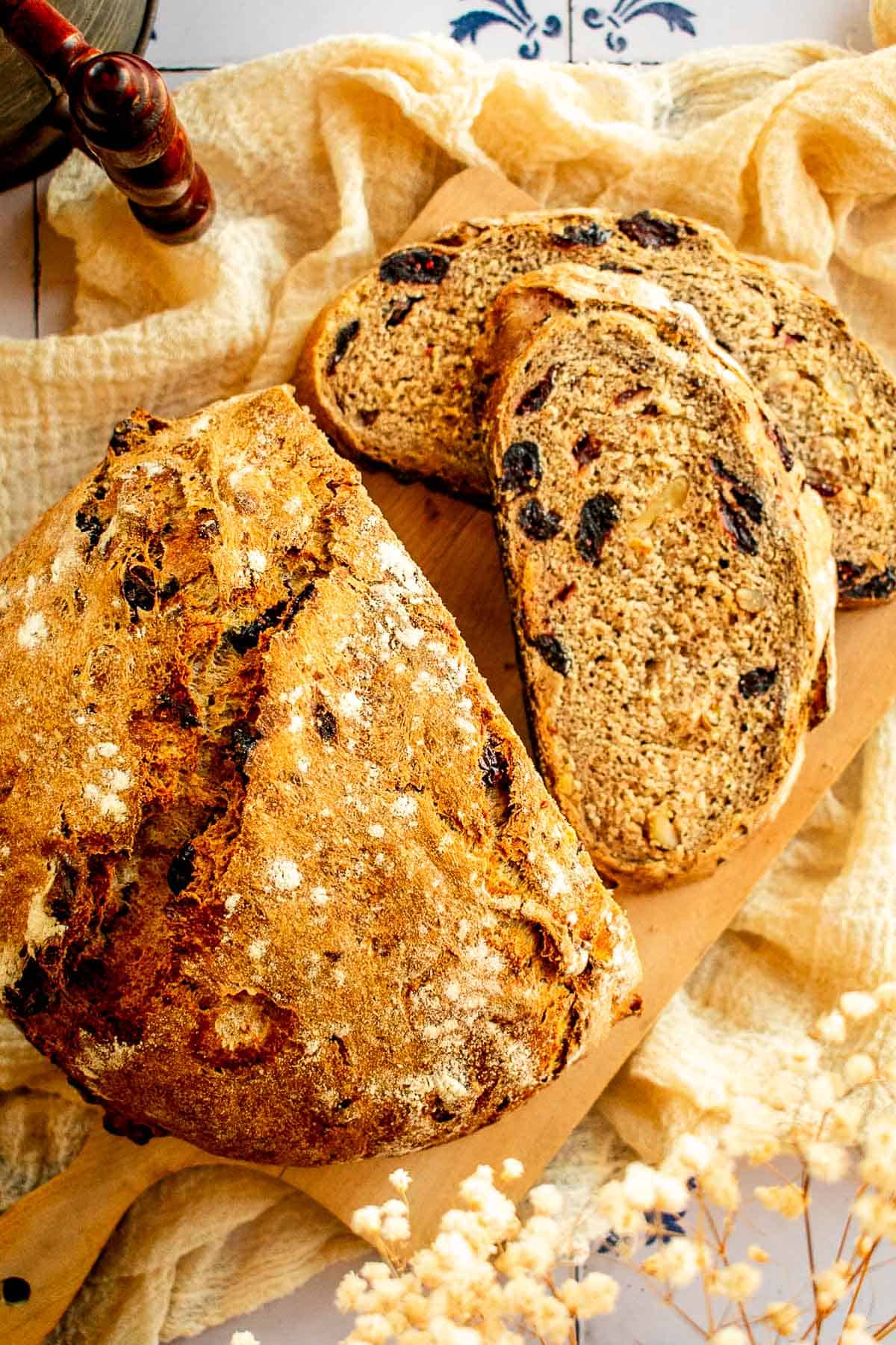 Cranberry bread with a crispy crust on a wood board on a linen.