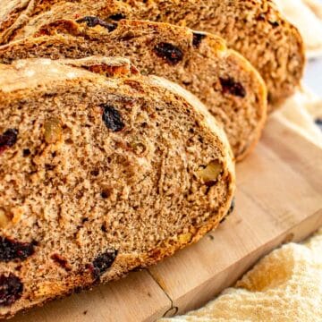 Slices of cranberry walnut bread on a cutting board.