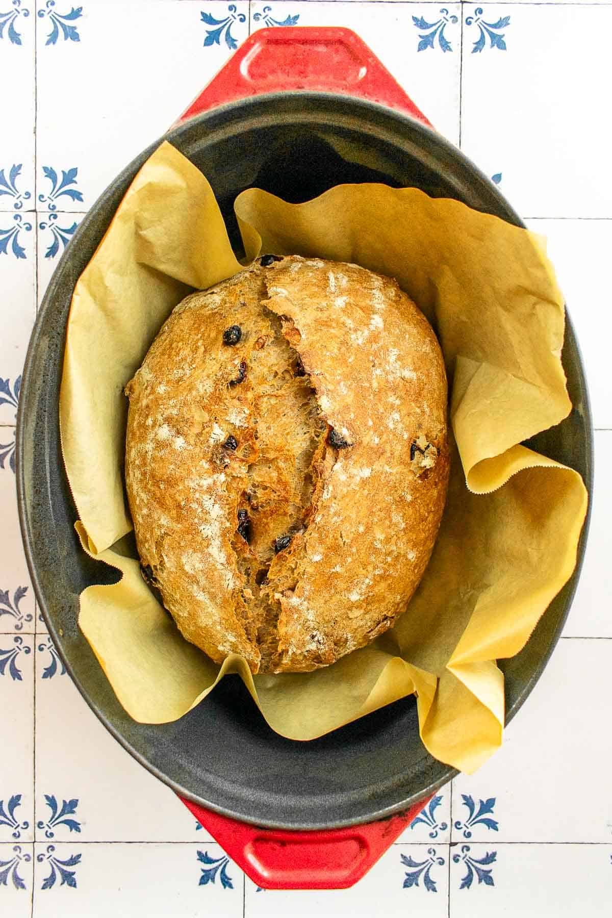 A loaf of baked artisan bread in a Dutch oven. 