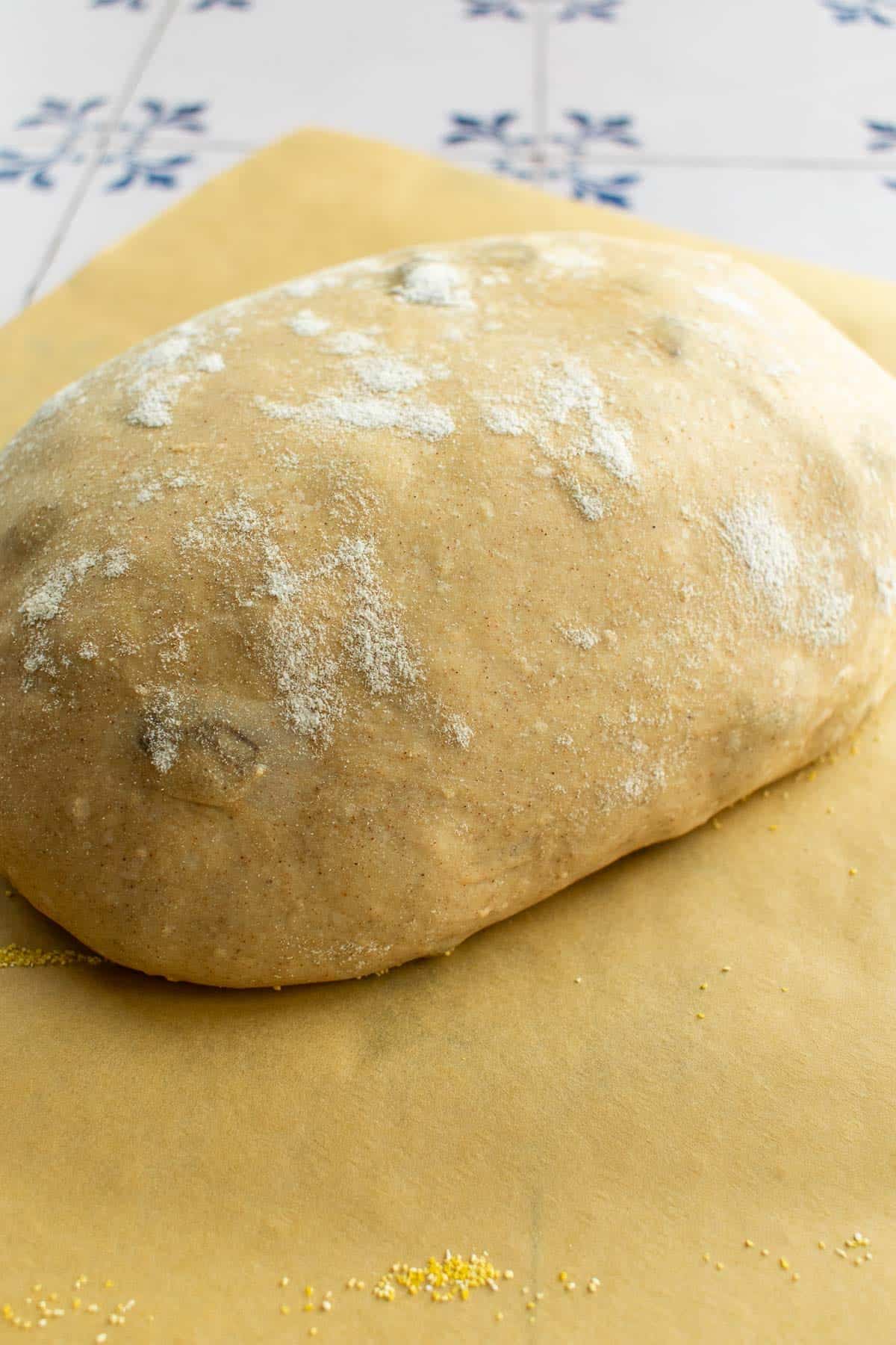 A ball of proofed bread dough on parchment paper.