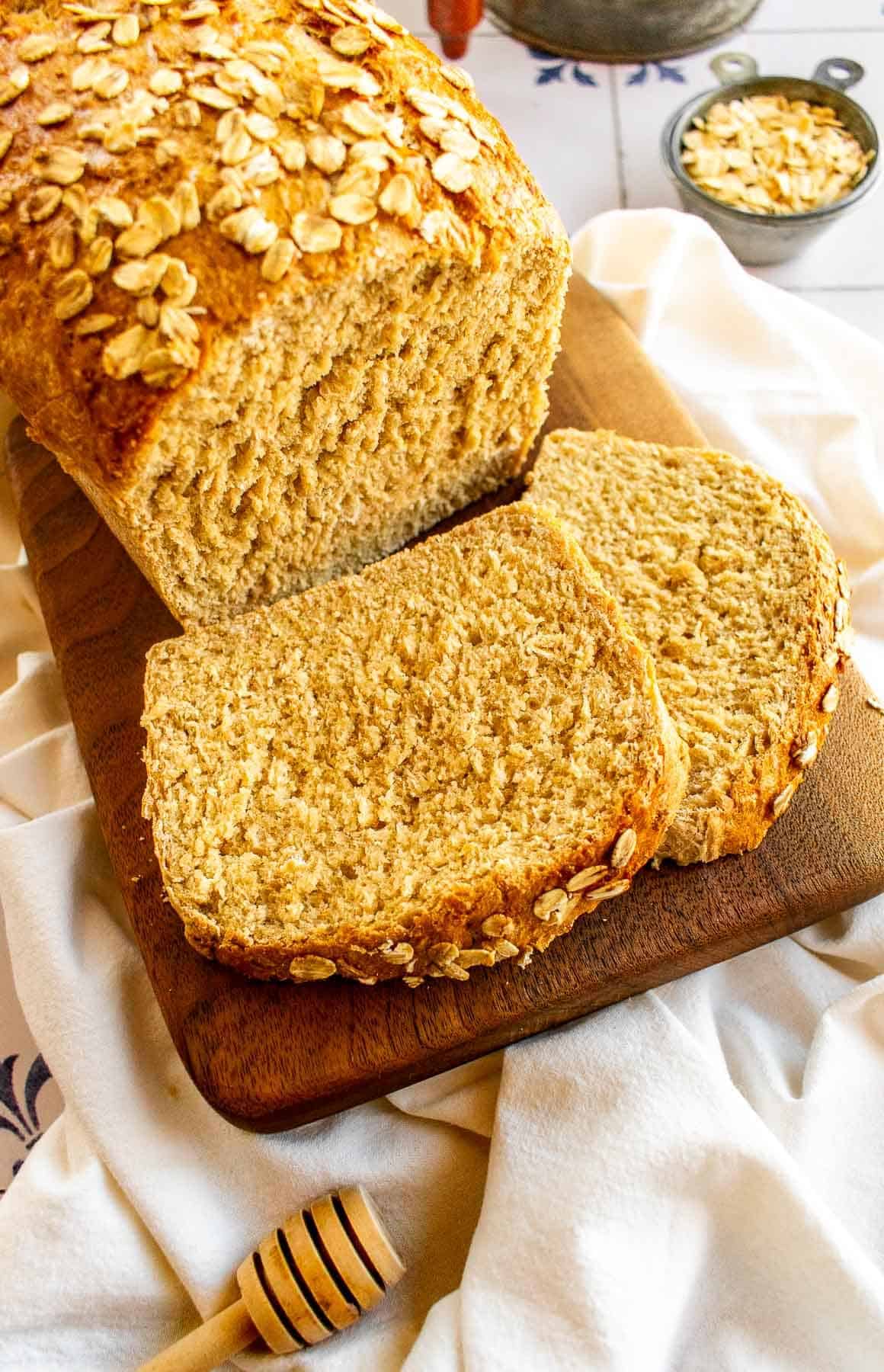 Two slices of honey oat bread next to the rest of the loaf.