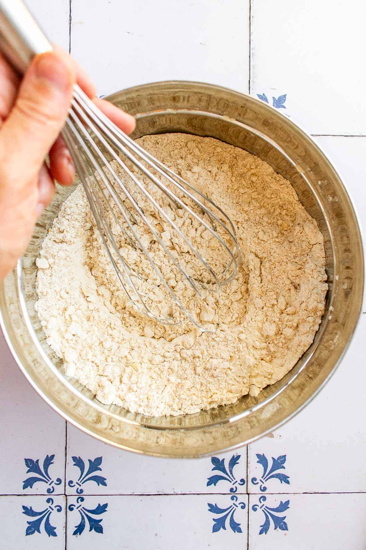 A hand whisking flour in a mixing bowl. 